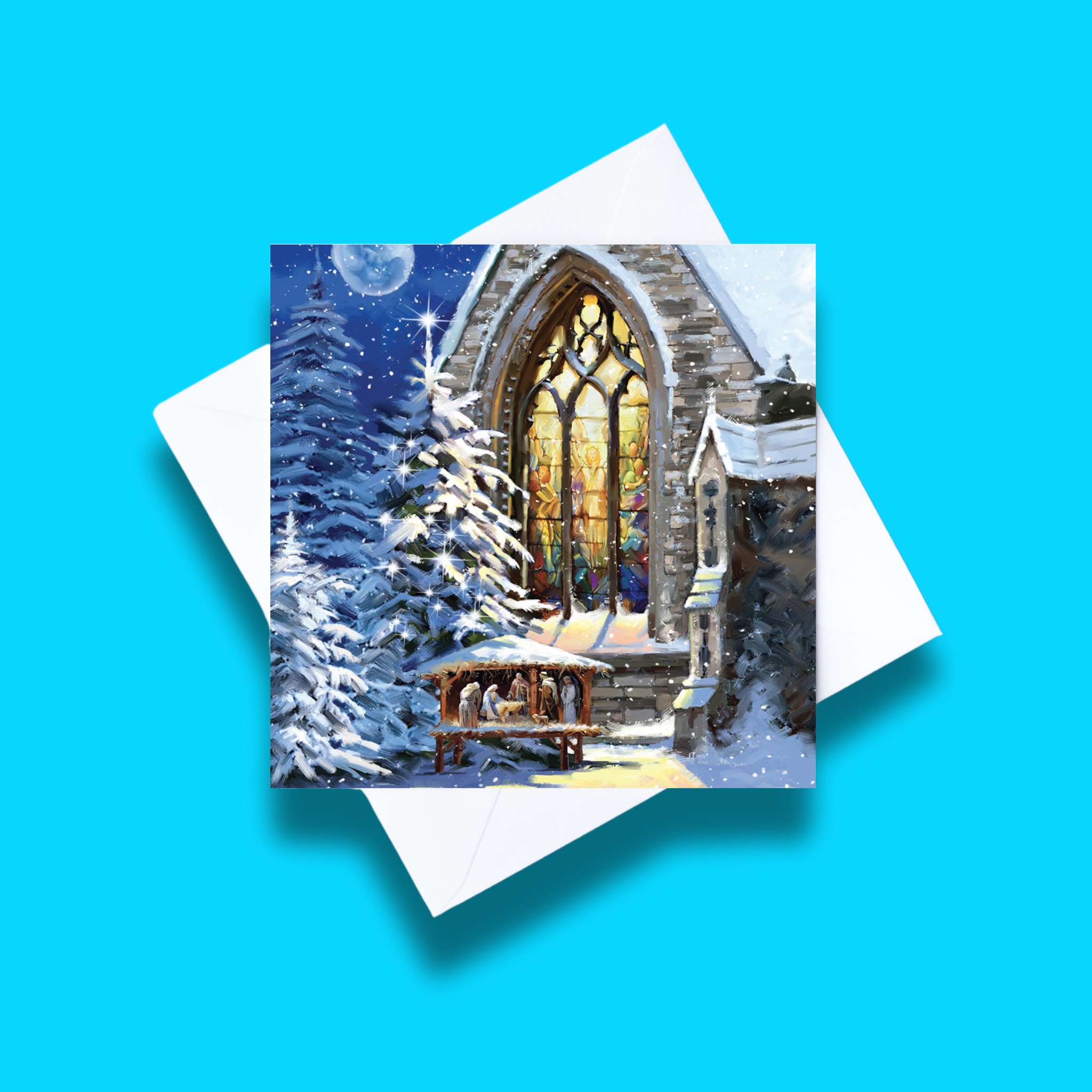 Church Nativity Christmas card with white envelope on a blue background. Card design features a church nativity scene with a church in the background on a starry night in a forest setting.