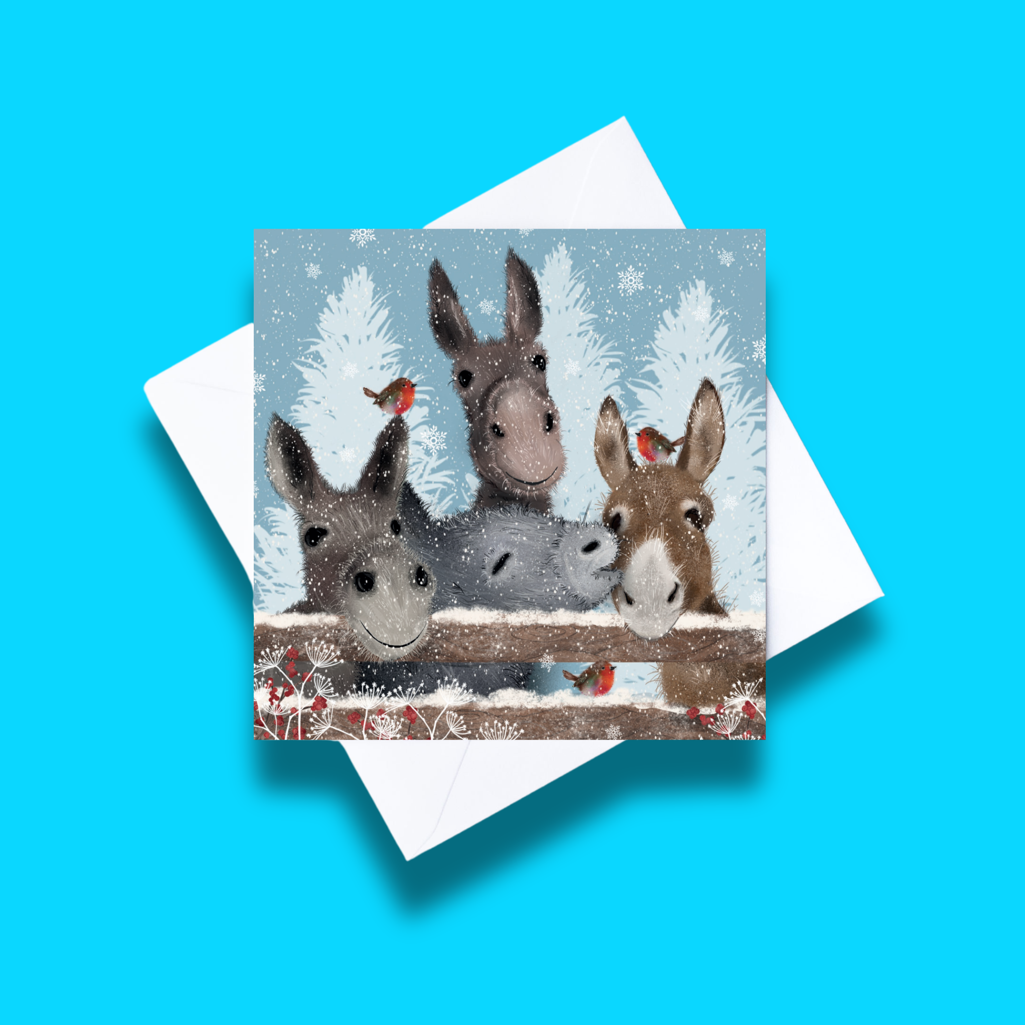 Donkeys and Robins Christmas card with white envelope on a blue background. Card design features four donkeys behind a fence and three robins standing in various places