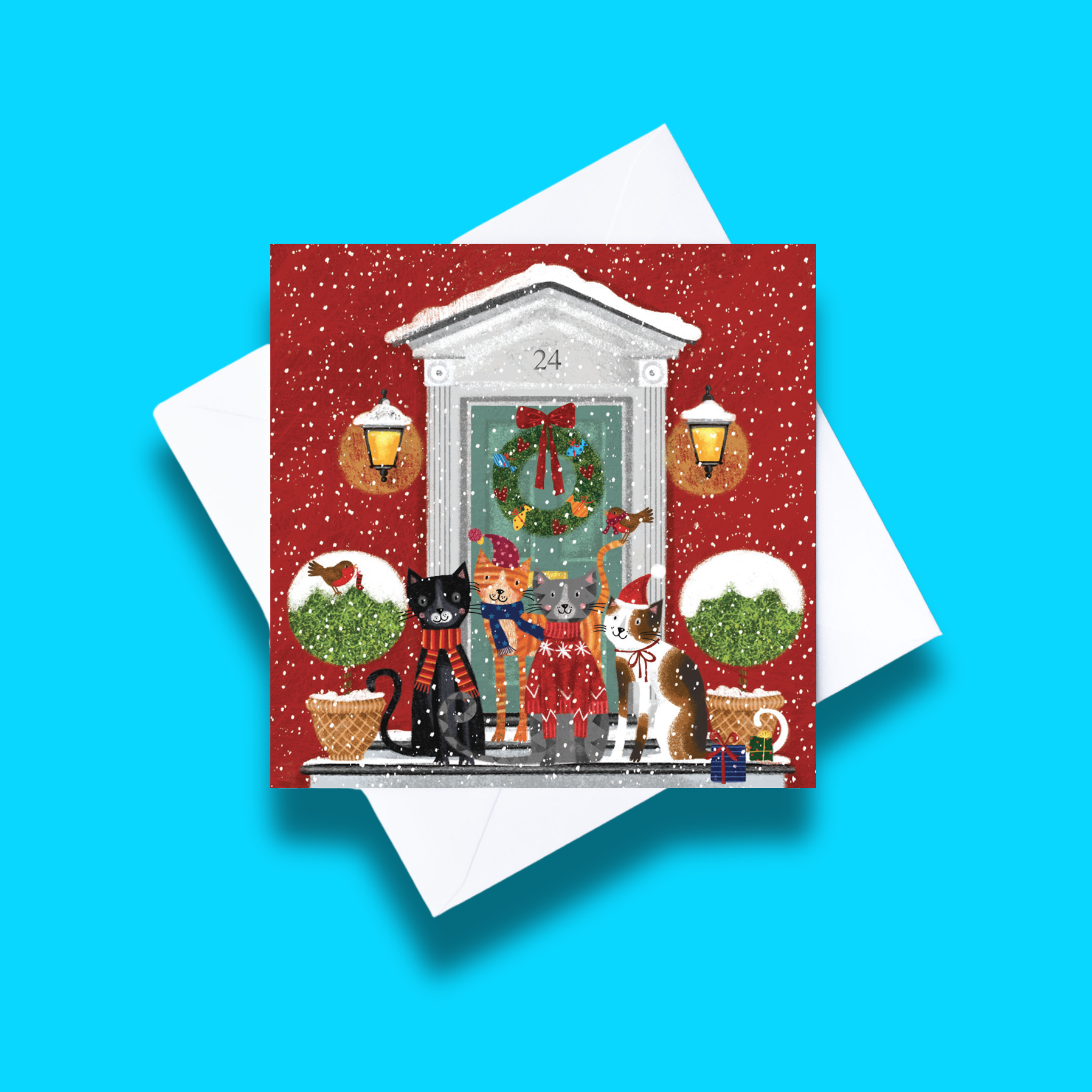 
Special delivery Christmas card with white envelope on a blue background. Card design features four festive cats in front of a red house with a grey door and snowy setting